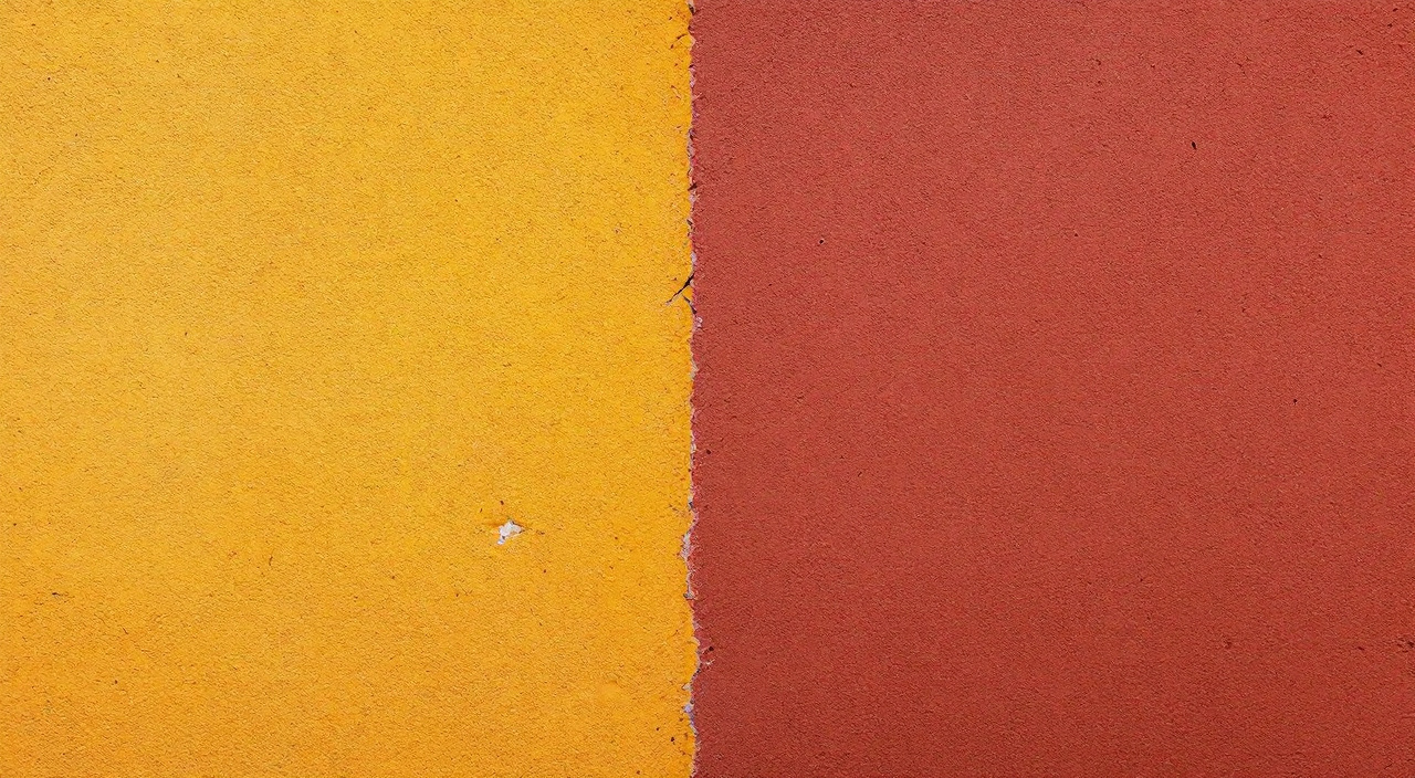 Mur enduit à la chaux où un panneau ocre jaune jouxte un panneau rouge d'oxyde de fer, plus pâle dans sa partie haute exposée au soleil.